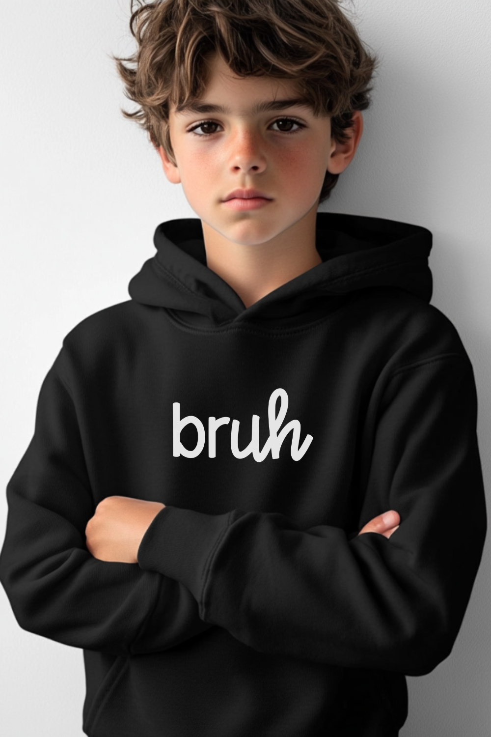 A boy wearing a sleek black unisex youth hoodie featuring a stylish cursive design that spells out "bruh." This modern streetwear hoodie is perfect for urban kids seeking trendy, comfortable, and edgy fashion.