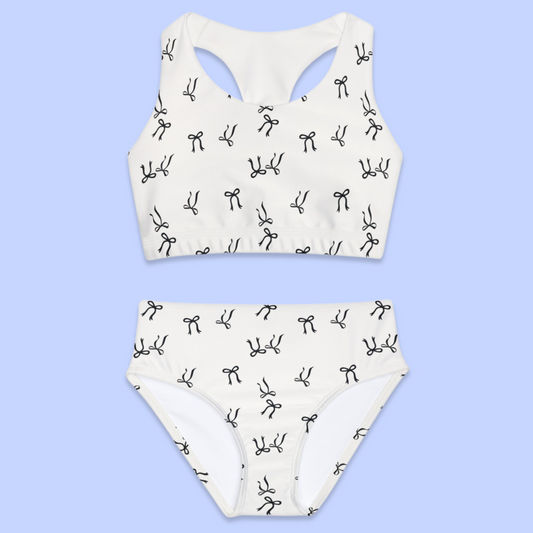 A stylish youth two-piece swimsuit featuring a chic black bow pattern, perfect for kids. Available in multiple colors with matching mommy-and-me and cousin crew swimwear options. Designed for comfort and fun in the sun, this swimsuit is ideal for mix-and-match summer looks.