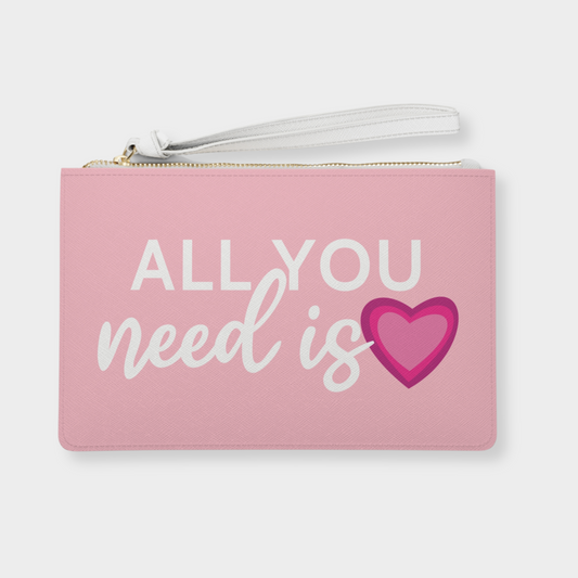Light pink vegan leather clutch bag with 'All You Need Is Love' design featuring a cute 3-layer heart, perfect for Valentine's Day gifts or year-round use. Features saffiano pattern finish, wrist strap, and two compartments for stylish and practical everyday use.